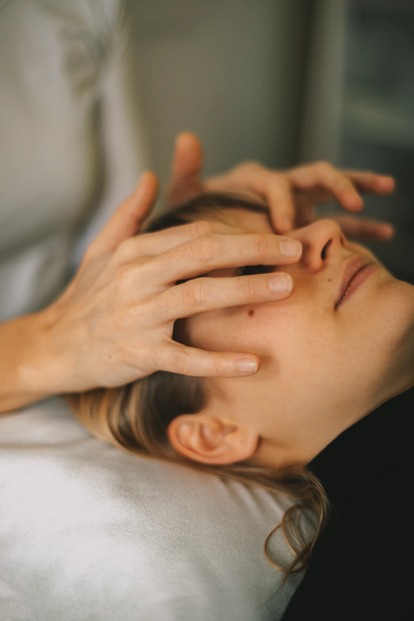 Person erhält eine entspannende Gesichtsmassage mit sanften Handbewegungen über den Augen.